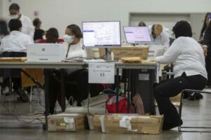Trabajadores del Departamento de Elecciones de Detroit revisan papeletas de voto ausente en la Junta Central de Conteo en el Centro TCF. Con una participación récord en la votación anticipada, los estadounidenses acudirán a urnas para las elecciones presidenciales. Foto: AFP.